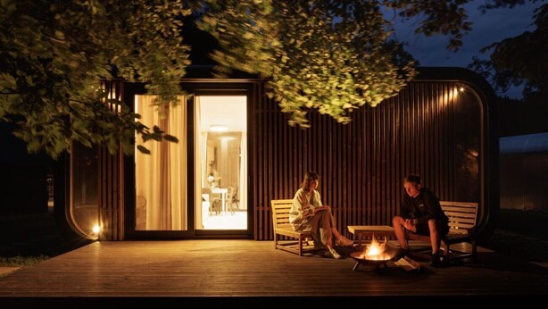 A modern, minimalist outdoor seating area with a fire pit, wooden benches, and a glass door leading to an interior space. - Base Camp Medvědín (Spindleruv Mlyn)