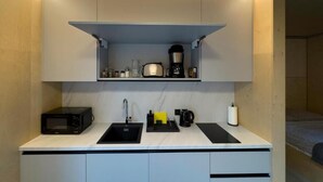A compact kitchenette with a microwave, coffee maker, and a small shelf above the counter. - Base Camp Medvědín (Spindleruv Mlyn)