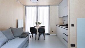 A compact living space with a sofa, dining table, chairs, and a kitchenette. - Base Camp Medvědín (Spindleruv Mlyn)