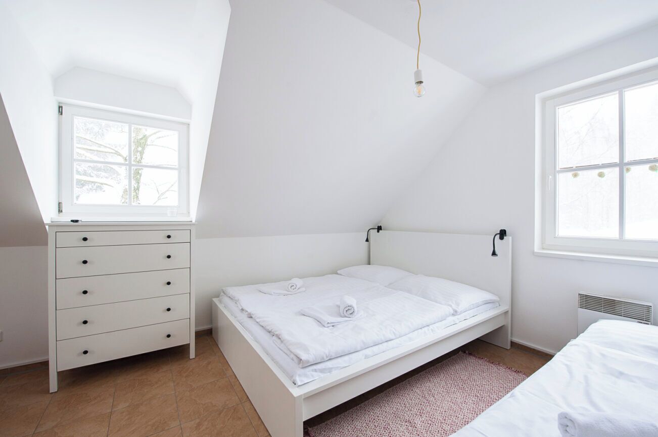 A bedroom with a single bed, a dresser, a window, and a radiator.