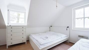 Un dormitorio con una cama individual, un aparador, una ventana y un radiador.