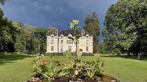 A large, historic building with a symmetrical facade, surrounded by a well-maintained lawn and mature trees. - Le Château du Breuil (Mazières-de-Touraine)