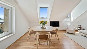 Een moderne loft met een eetgedeelte, inclusief een ronde tafel, stoelen en een vaas met zonnebloemen.