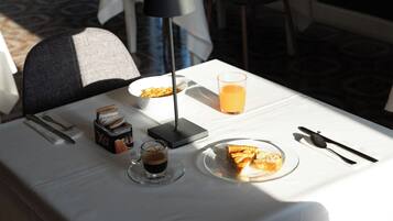 Ein Esstisch mit einer Speisenplatte, einem Orangensaftglas, einer Kaffeetasse und einer Taschentuchbox.