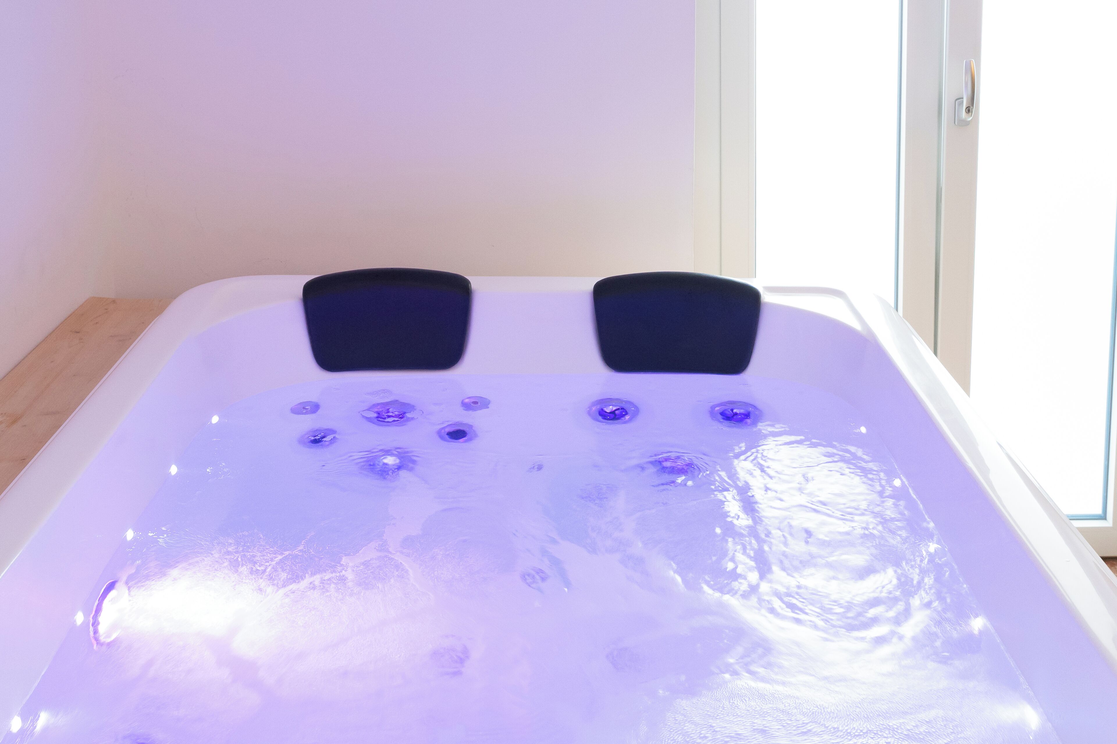 Ein Whirlpool mit zahlreichen Düsen und einer Glastür im Hintergrund.