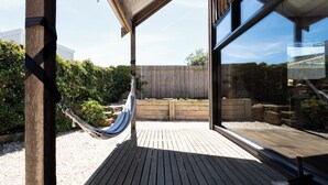 Uma rede em um deck de madeira com vista para um jardim e um edifício.