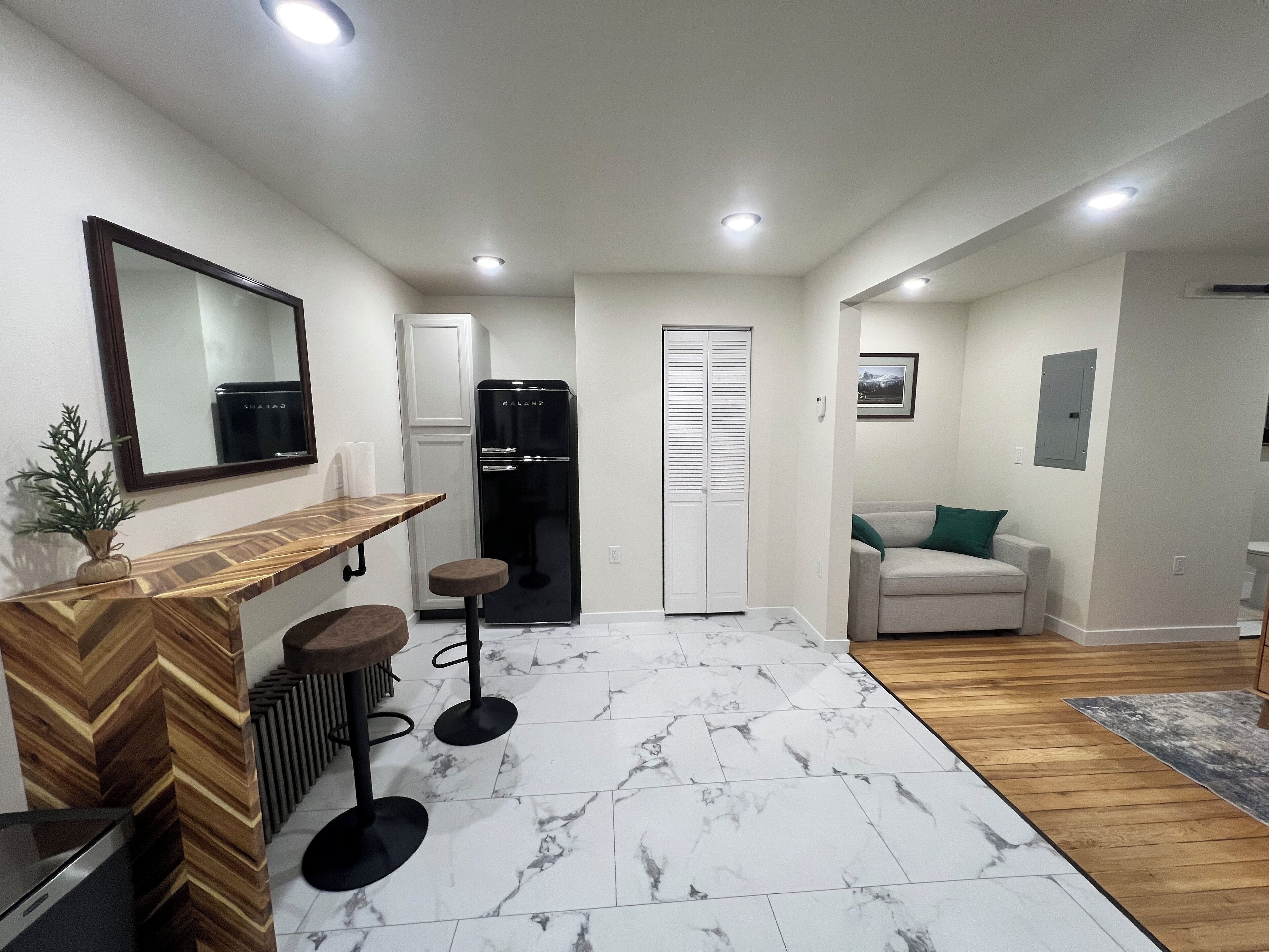 A modern kitchen with a built-in refrigerator, a wooden countertop, and a marble-tiled floor.