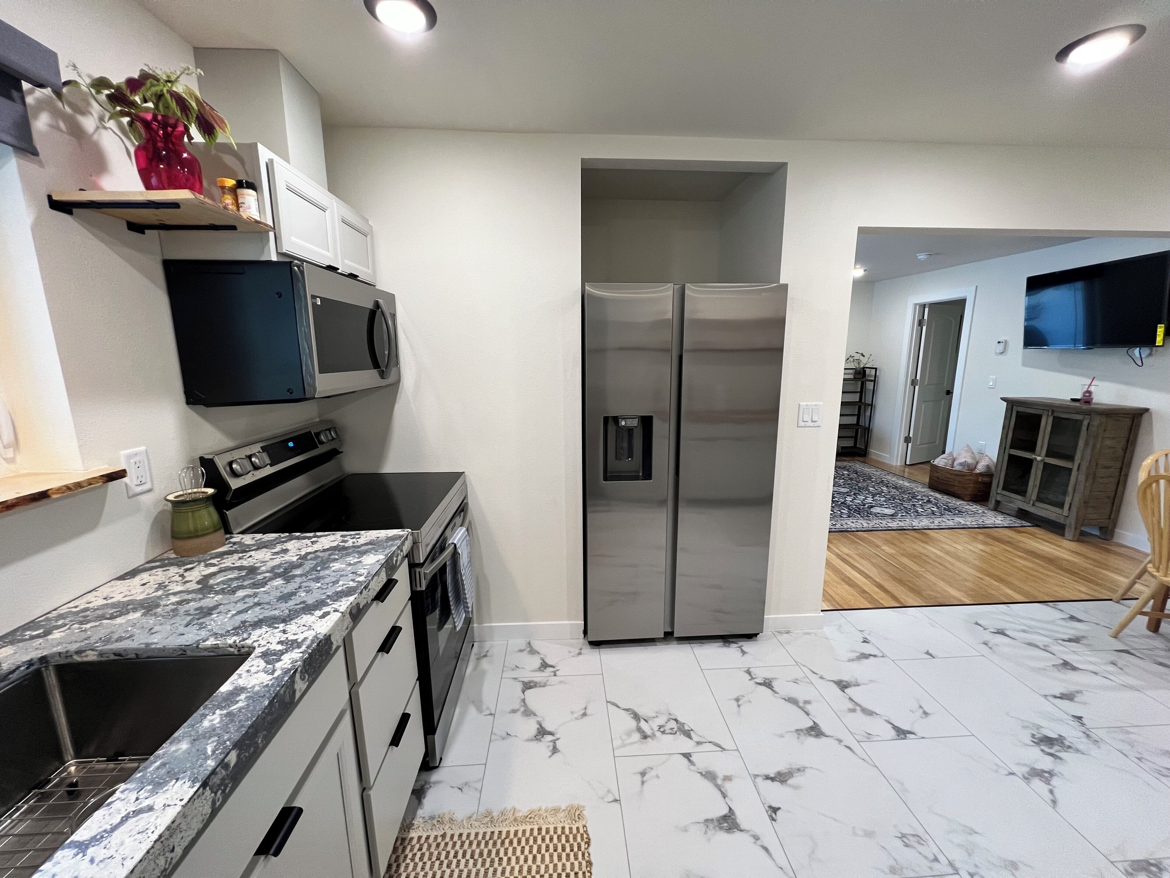 A modern kitchen with stainless steel appliances, a marble countertop, and a built-in oven.
