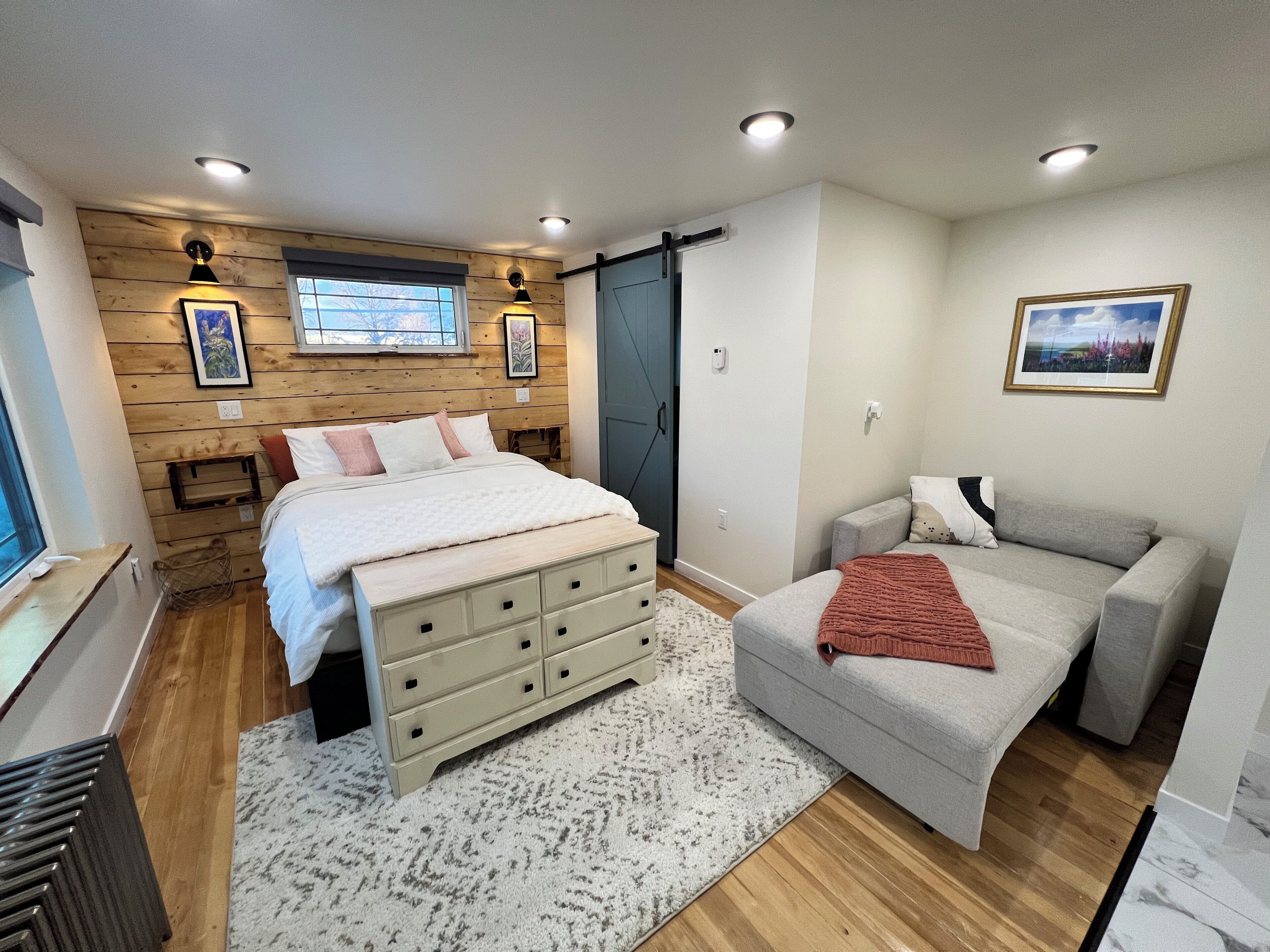 A bedroom with a bed, dresser, and a sofa.