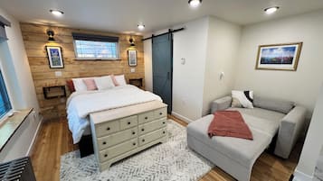 A bedroom with a bed, dresser, and a sofa.