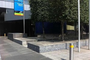 A metro station platform with a digital display, steps, and a tree. - A Cozy & Comfy 2BR Apt Near Victoria Market (Melbourne)