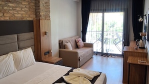 A modern hotel room with a large bed, a sofa, a desk, and a balcony with a view. - SAND GARDEN (Bodrum)