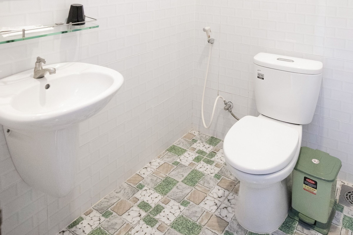 A bathroom with a white sink, toilet, and shower area.
