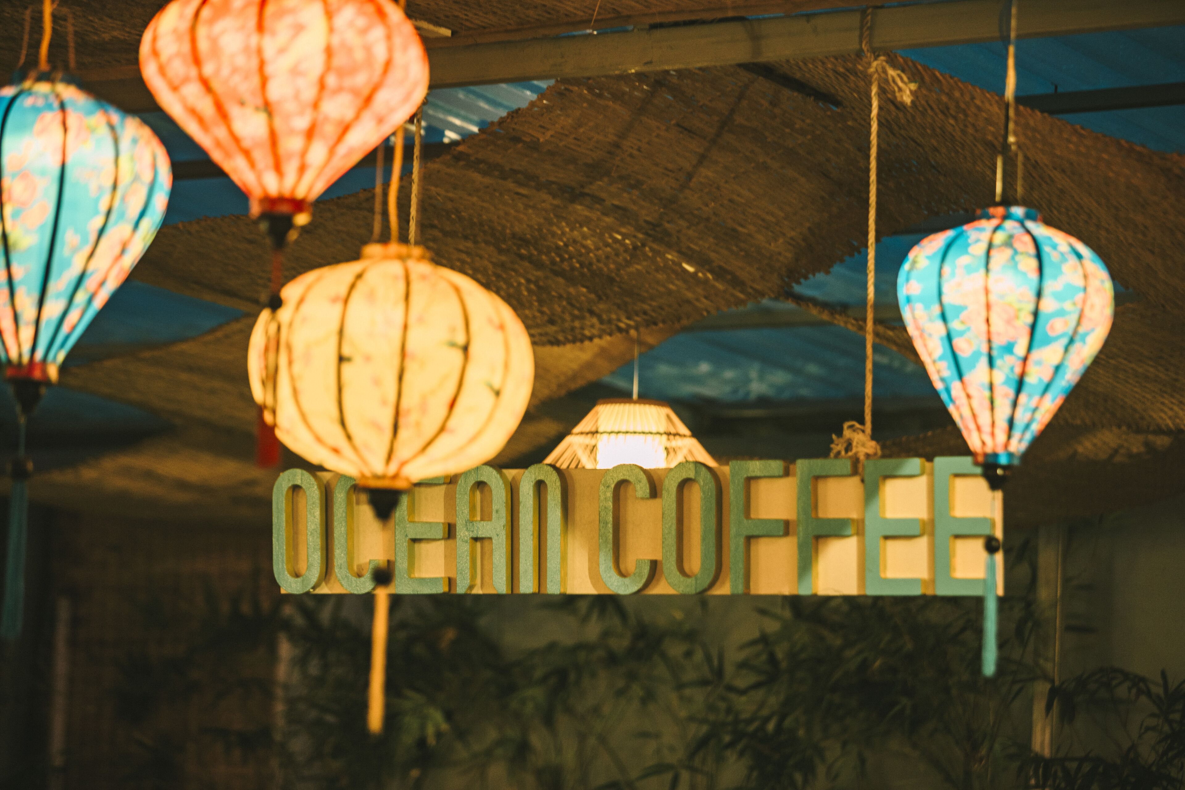 A sign for 'Ocean Coffee' with hanging lanterns above.
