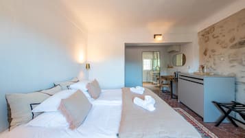 Una habitación de hotel con cama, escritorio y baño visible a través de una puerta abierta.