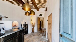 A kitchen with a black countertop, a wooden door, and a stone floor.