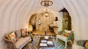 A cozy interior with a sofa, armchairs, a coffee table, and a hanging light fixture.