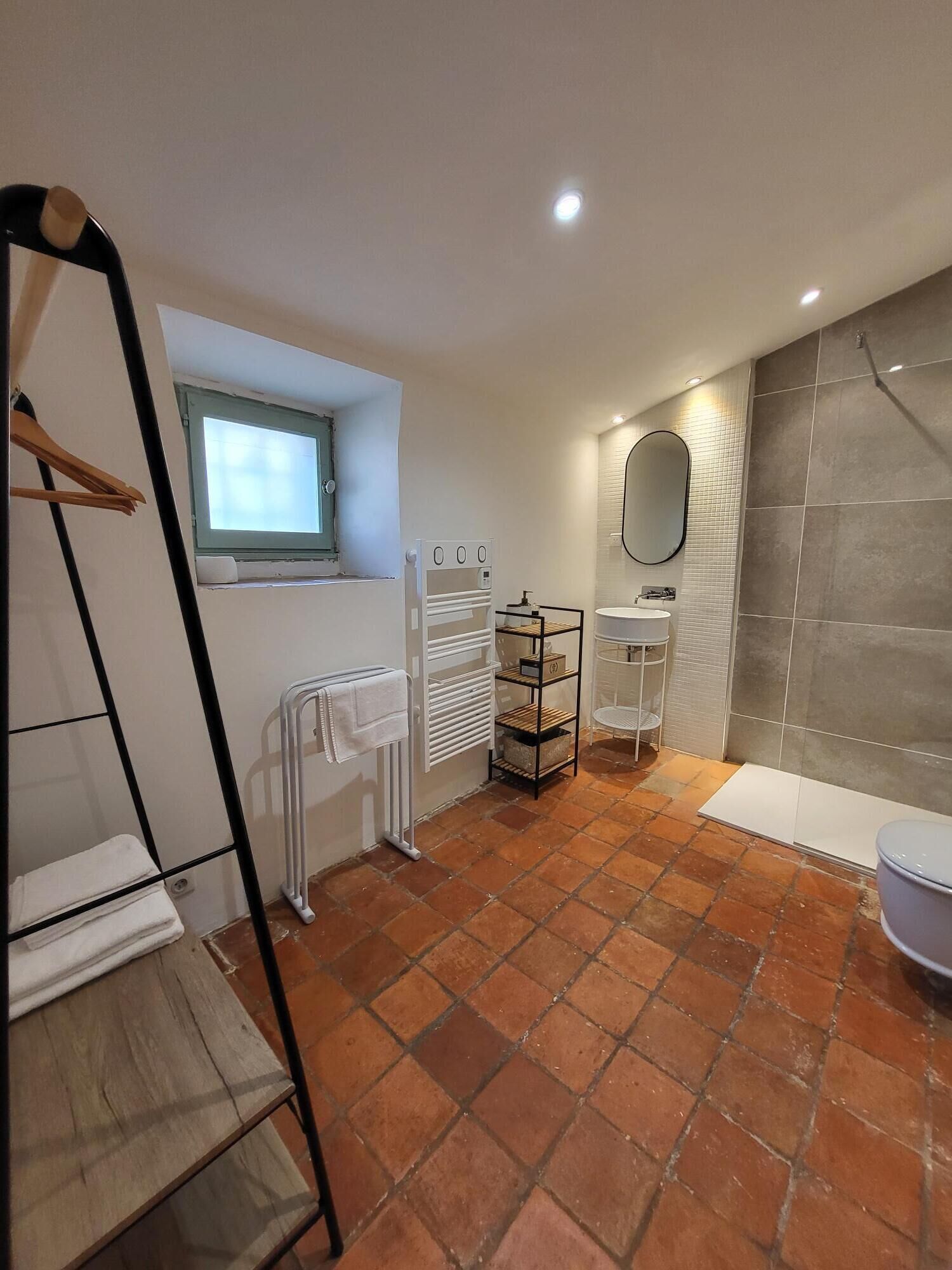 A modern bathroom with a white sink, a mirror, a towel rack, and a radiator.