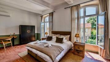 Un dormitorio con una cama grande, un escritorio de madera, un armario y vistas al exterior.