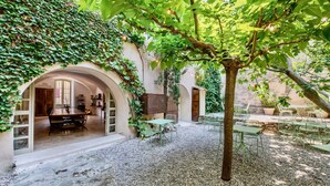 An outdoor courtyard with a gravel floor, green metal furniture, and a tree.
