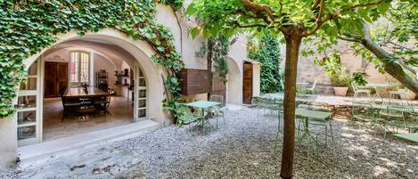 An outdoor courtyard with a gravel floor, green metal furniture, and a tree.