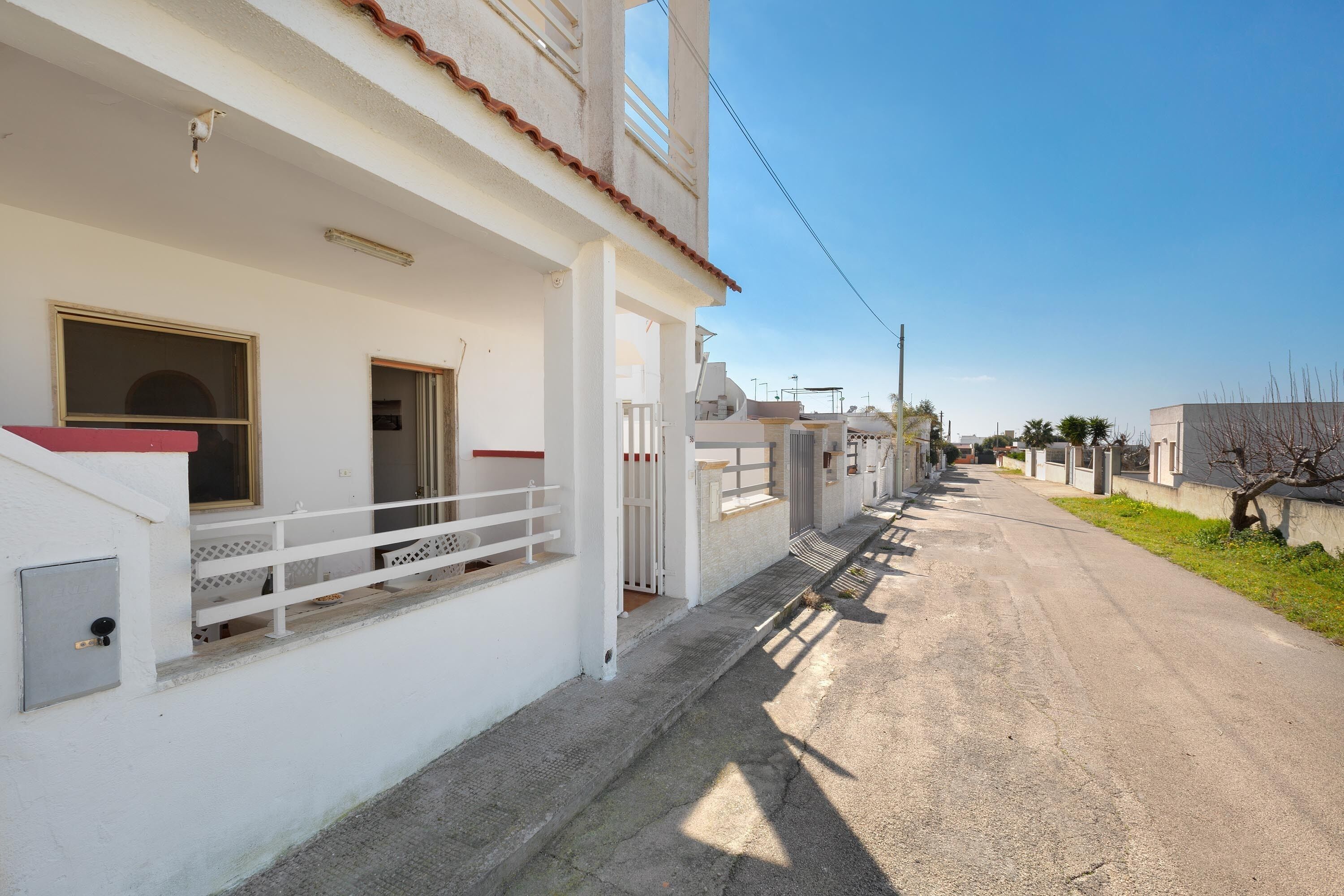 A white building with a balcony, a door, and a window.