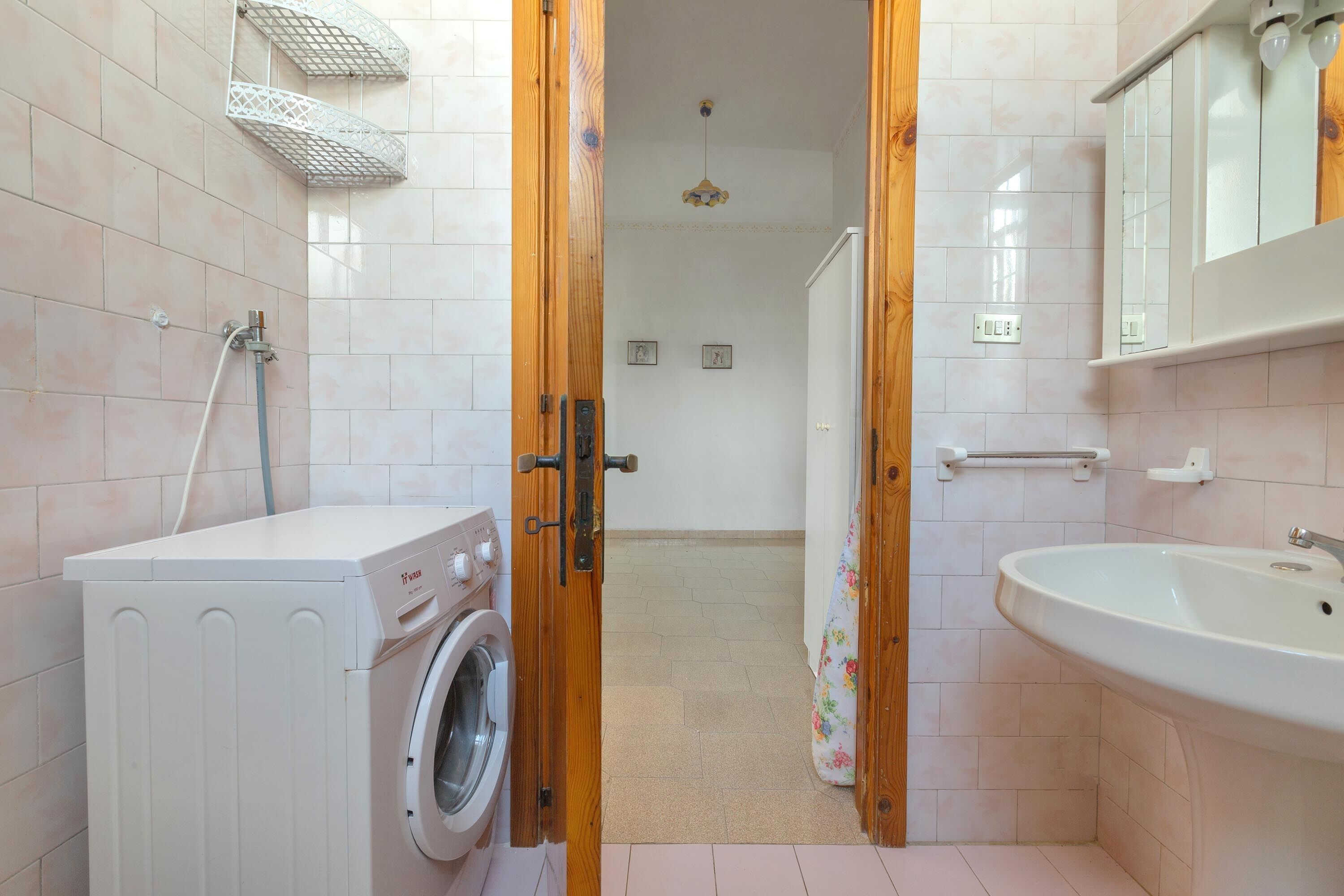 Une petite salle de bain équipée d’un lave-linge, d’un lavabo et d’une douche.