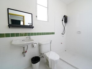 A bathroom with a white sink, toilet, and shower. There is a mirror above the sink and a small trash bin next to it. - RoomQuest Hotel Pratunam (Bangkok)