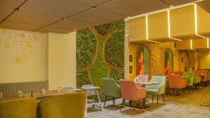A restaurant with a green wall, colorful chairs, and a tiled floor. - Amritara Maa Katra (Reasi)