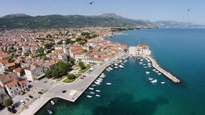 An aerial view of a coastal town with a marina, buildings with red-tiled roofs, and a clear blue sea. - Apartment Antonio with balcony, near the beach (Kaštel Novi)