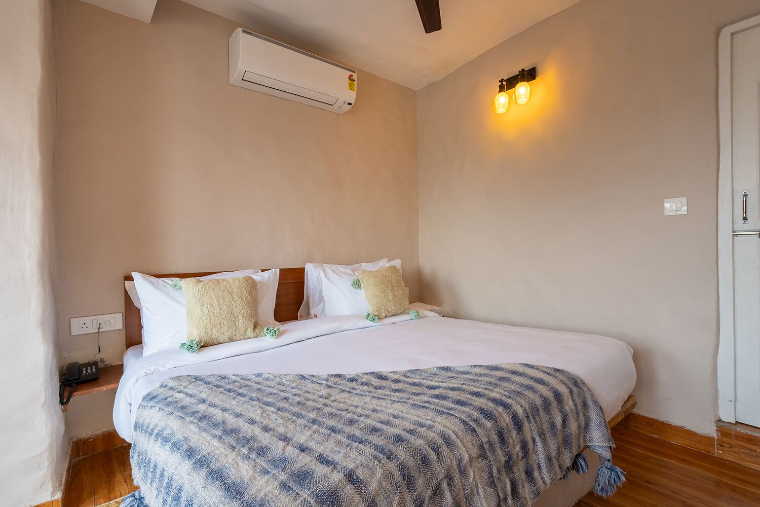 Une chambre à coucher comprenant un lit, un climatiseur fixé au mur, un téléphone sur la table de chevet et un luminaire fixé au mur.