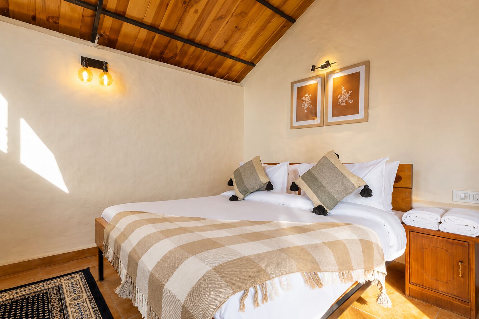 Habitación de hotel con cama, mesita de noche e iluminación en la pared.
