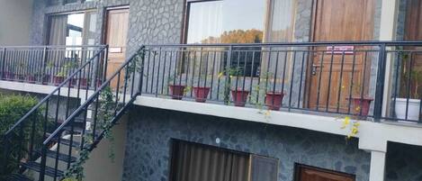 A multi-story building with a stone facade, balconies with potted plants, and a staircase leading to the upper floors.