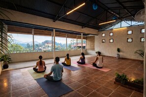 A spacious indoor yoga room with large windows offering a view of the outdoors. - MAATI Resort by The Lake Hill (Nainital)