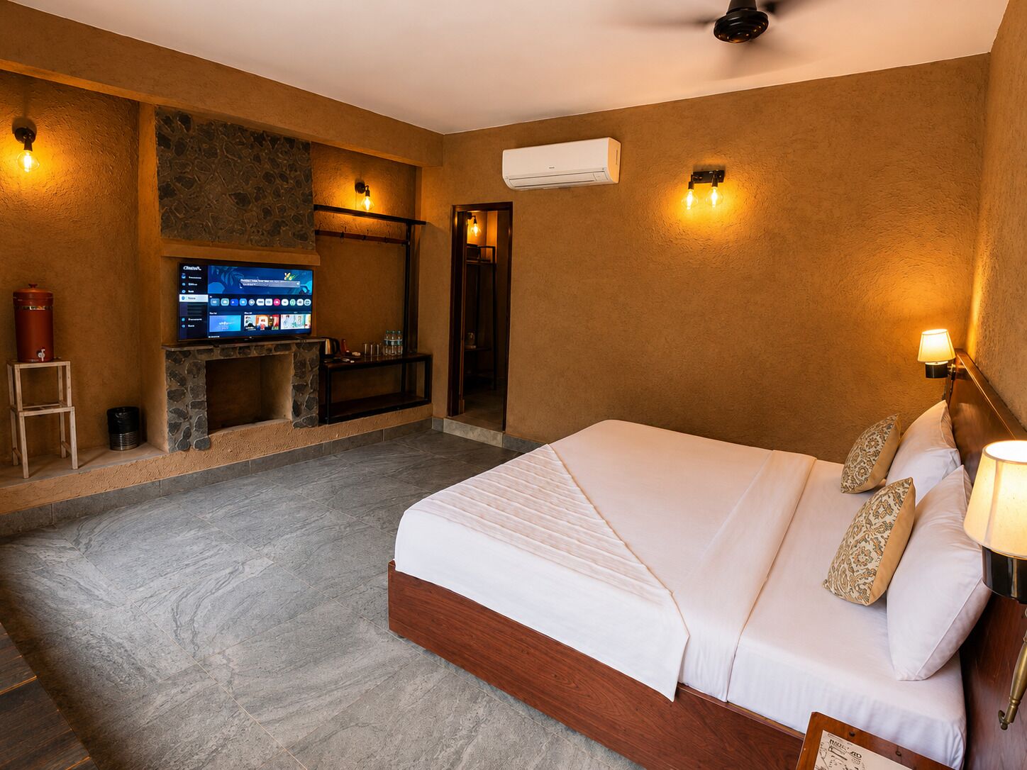 A hotel room with a bed, a television, a fireplace, and a shower.