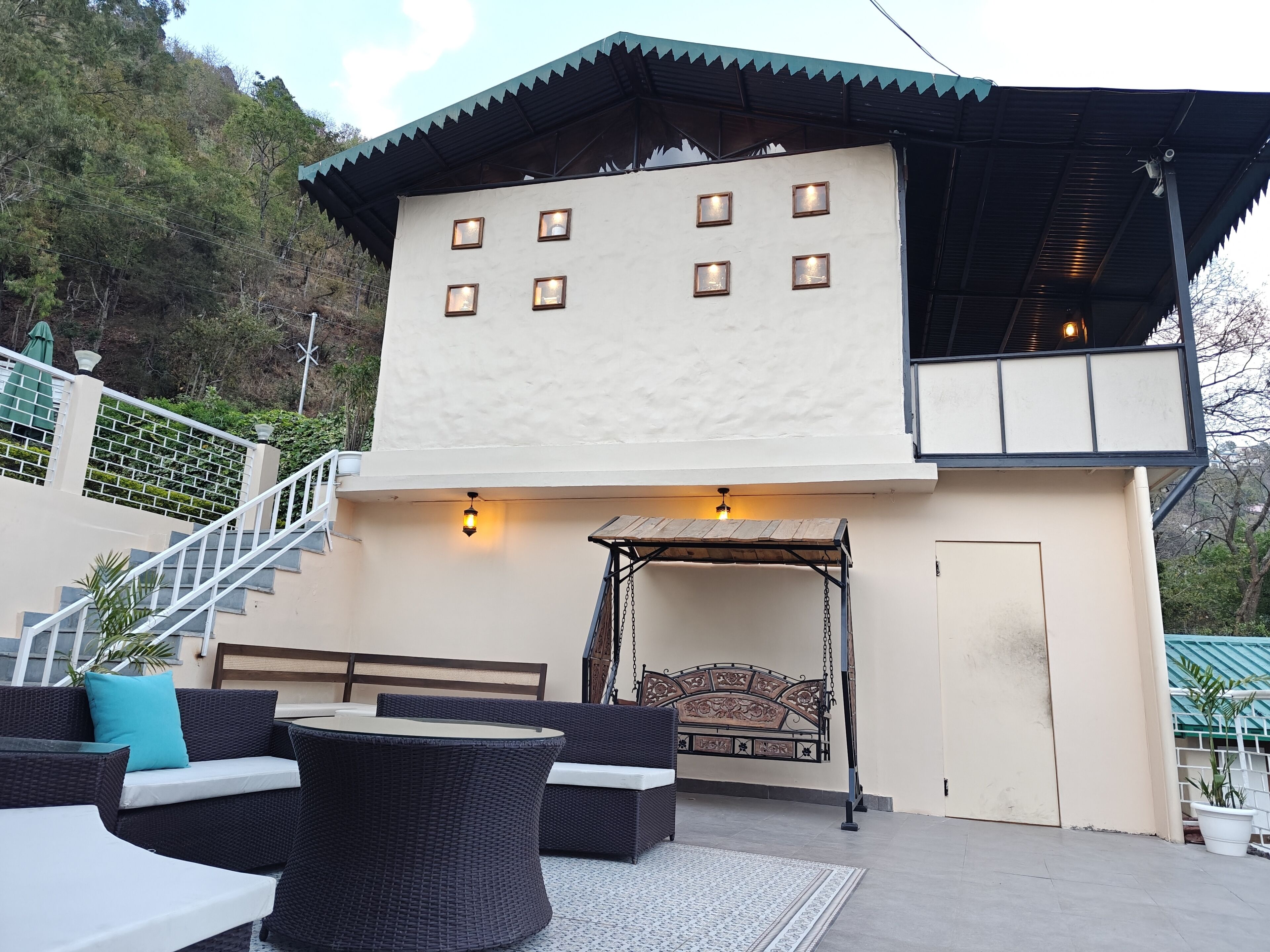 Un edificio de dos pisos con balcón, zona de estar al aire libre y una escalera.
