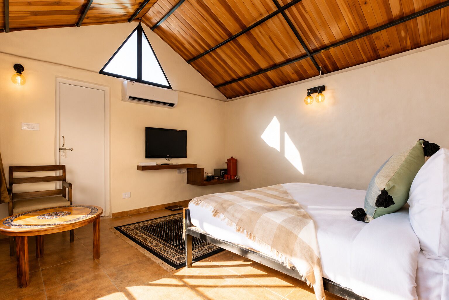 Una habitación con una cama, televisión, una silla y una mesita.