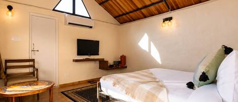 Una habitación con una cama, televisión, una silla y una mesita.