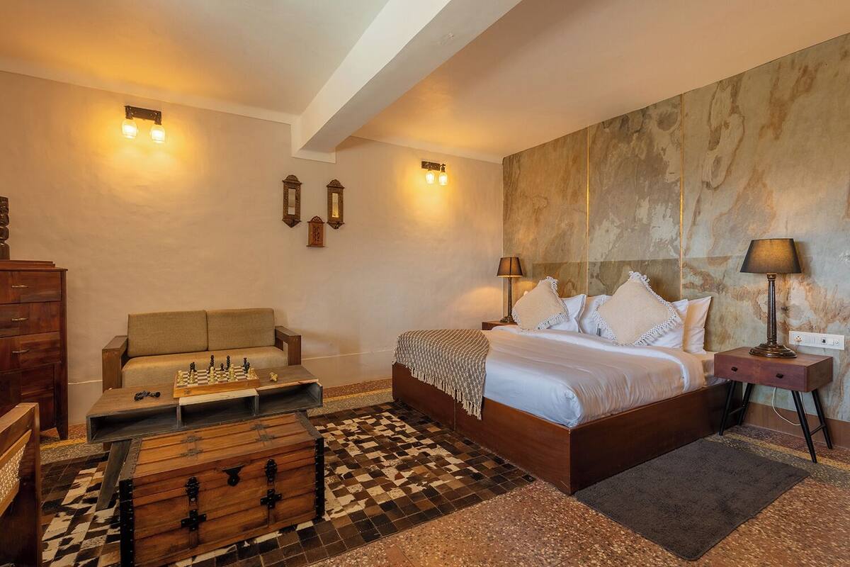 A bedroom with a wooden bed, a sofa, a chessboard, and a chest of drawers.