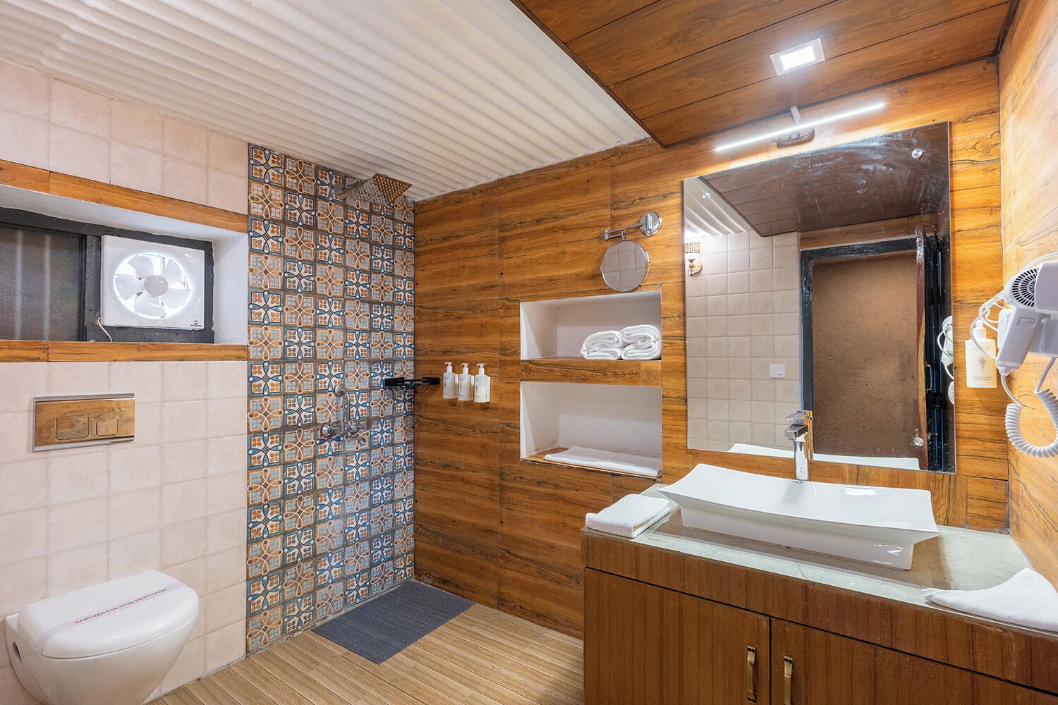 A bathroom with a shower, toilet, sink, and a mirror.