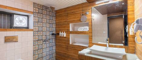 A bathroom with a shower, toilet, sink, and a mirror.