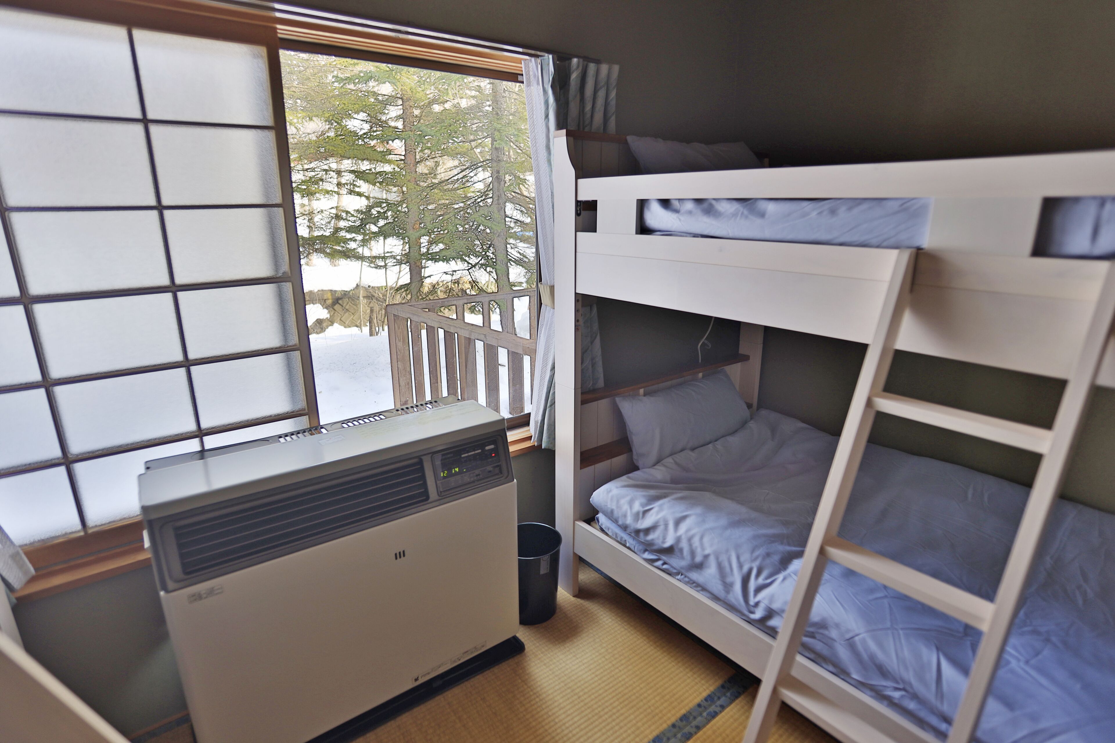 Dormitorio con literas, ventana, calefacción y vistas a árboles.