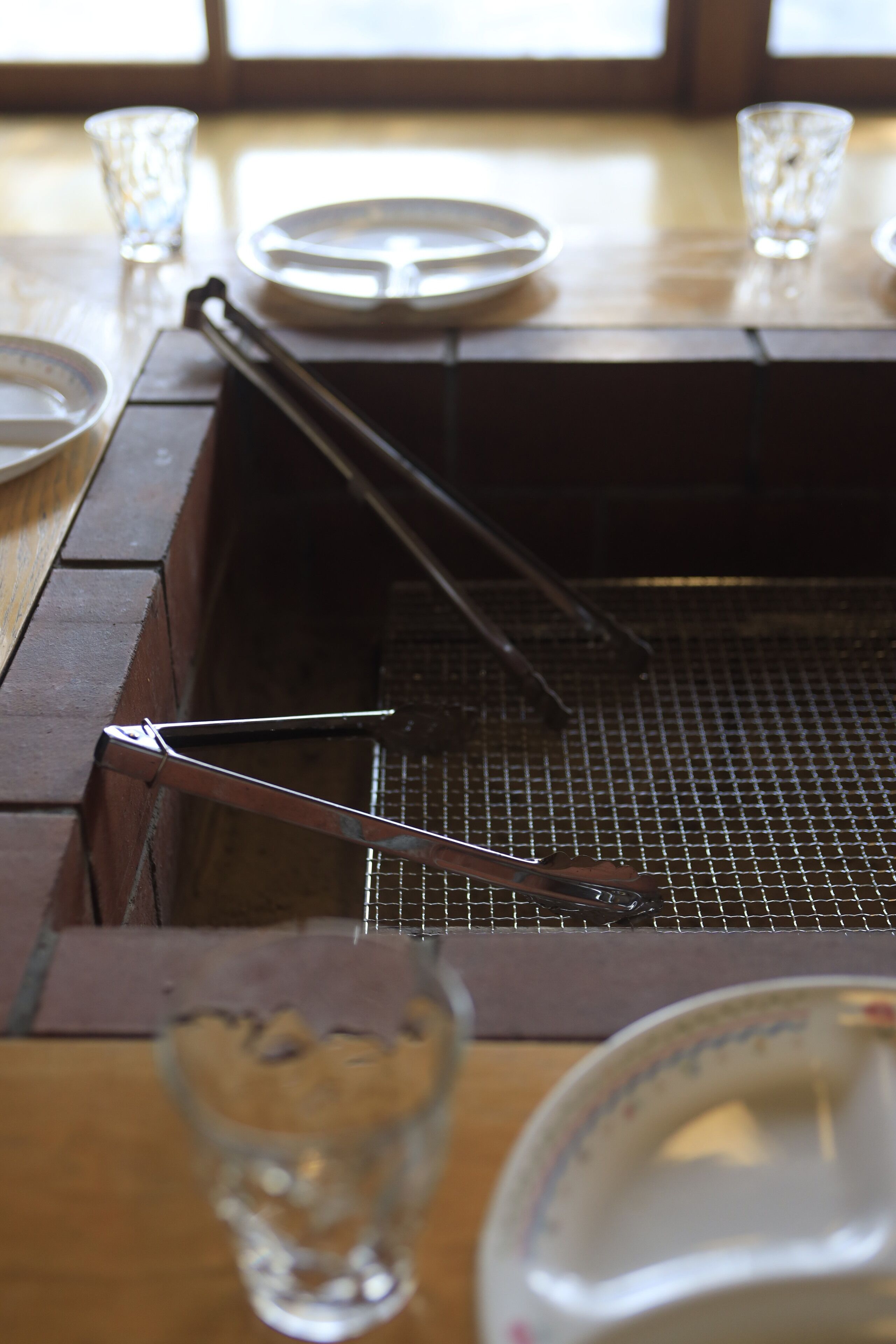 A kitchen with a metal griddle, a glass, and a plate on the table.