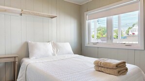 Une chambre à coucher avec un lit, des oreillers, une fenêtre et une pile de serviettes.