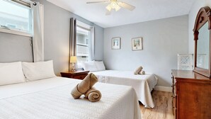 A hotel room with two beds, a wooden dresser, a ceiling fan, and two framed pictures on the wall. - Sand Life #1 by Bayley Vacation Rentals (Old Orchard Beach)