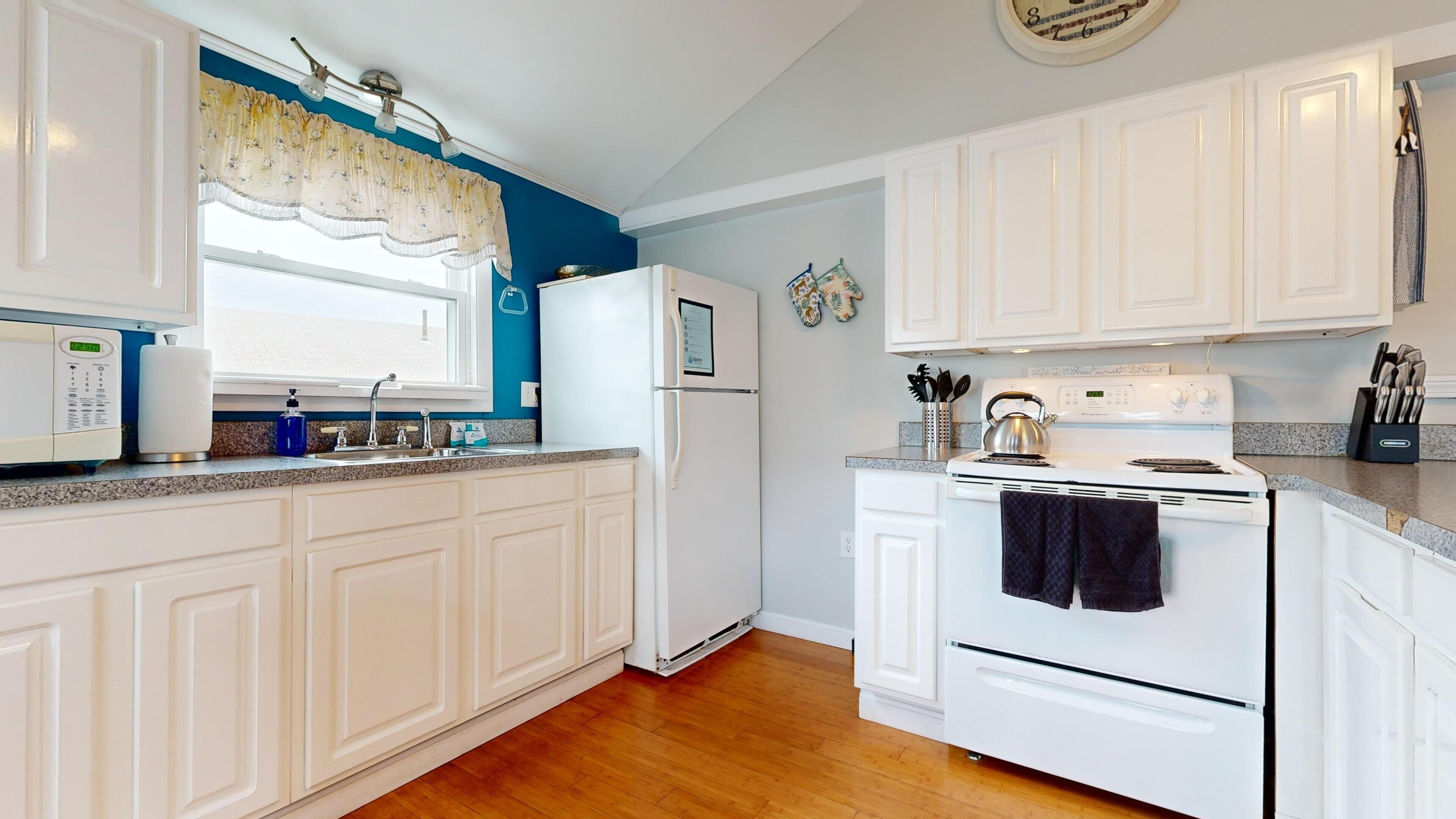 A kitchen with white cabinets, a stainless steel kettle, and a built-in oven.