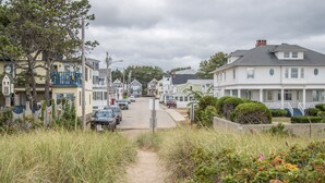 A residential street with houses, a sandy path, and parked cars. - Sand Life #2 by Bayley Vacation Rentals (Old Orchard Beach)