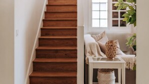 A wooden staircase leading to a room with a white radiator, a window, and a plant. - Le Domaine de la Source (Pennedepie)