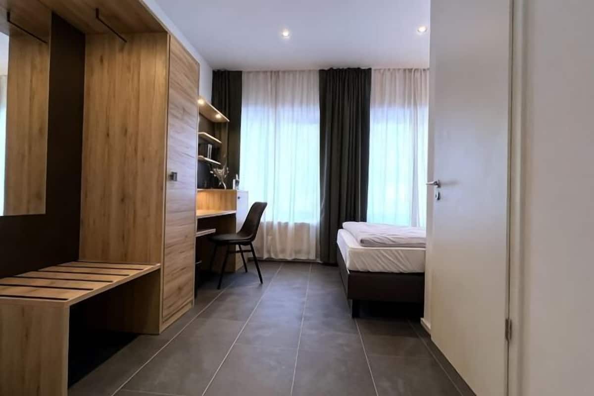 A compact hotel room with a bed, a desk, and a chair.