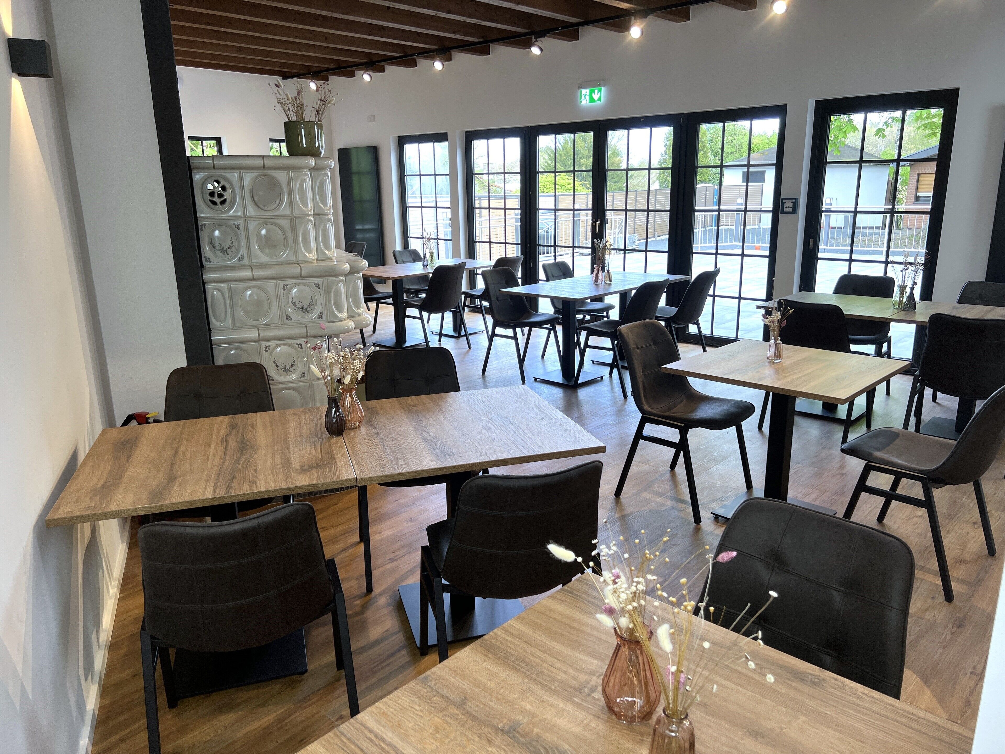 A spacious dining area with multiple tables and chairs, large windows, and a modern interior design.